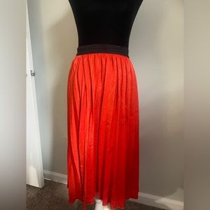 Red pleated skirt with black band around the waist